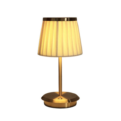 Gold table lamp with pleated shade on a white background