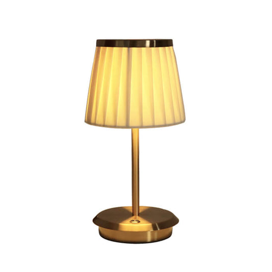 Gold table lamp with pleated shade on a white background