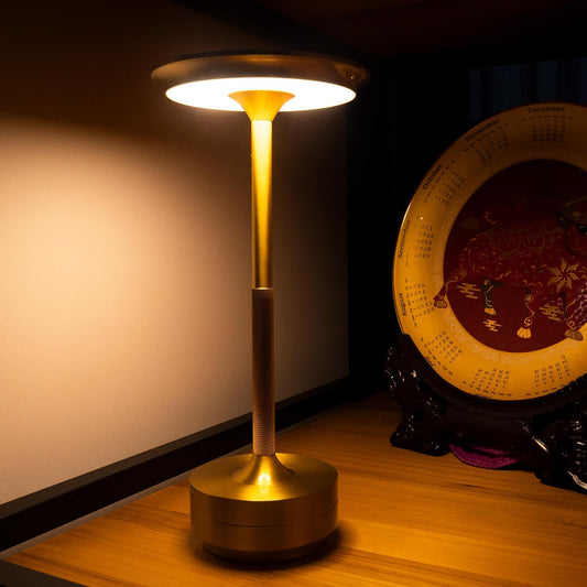 Gold floor lamp on a wooden floor with a decorative plate in the background