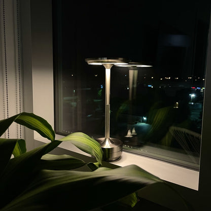Silver outdoor lamp on a windowsill with a nighttime cityscape view